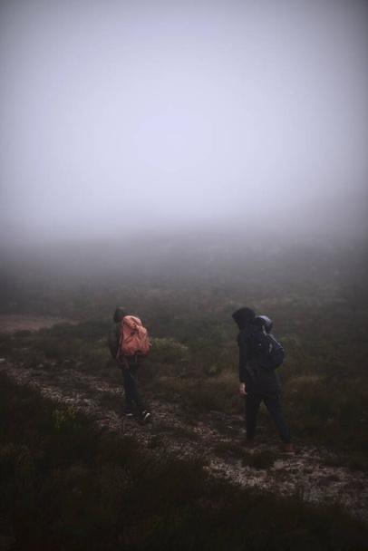 El senderismo siempre es una buena idea. dos amigos varones haciendo senderismo en las montañas en un día de niebla - Foto, imagen