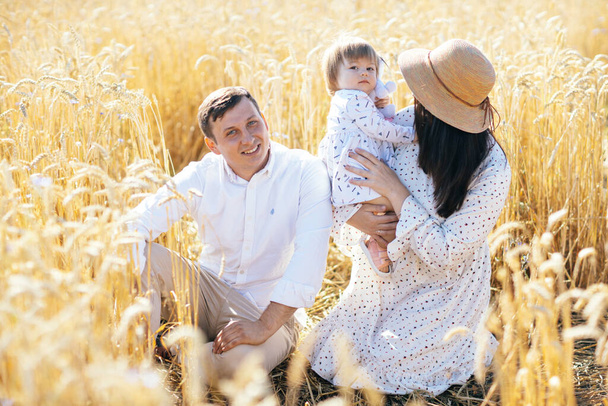 Bonne enfance, famille marchant sur le champ de blé. Mère, père et petite fille s'amusent ensemble en plein air. Parents et enfants jouent dans la prairie d'été. Photo de haute qualité - Photo, image