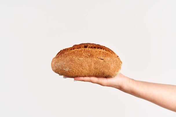 Homemade multigrain bread in woman hand over white background. Bakery, food concept - Fotoğraf, Görsel