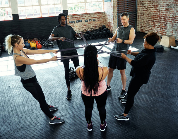 Dingen veranderen. een fitnessgroep trainen met verzetsbanden in hun sessie in de sportschool - Foto, afbeelding