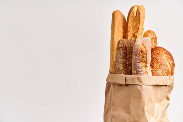 Different types of french bread baguettes in paper bag over white background with copy space. Bakery, delicious food concept - Photo, image
