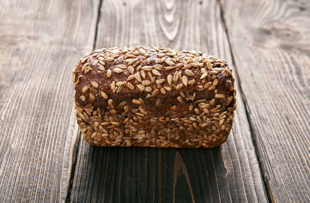 Loaf of fresh made rye multigrain bread on wooden table background. Bakery, food concept - Фото, зображення