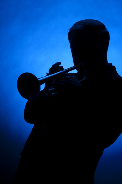 Trumpetti pelaaja siluetti vastaan sininen paikalla valo
 - Valokuva, kuva
