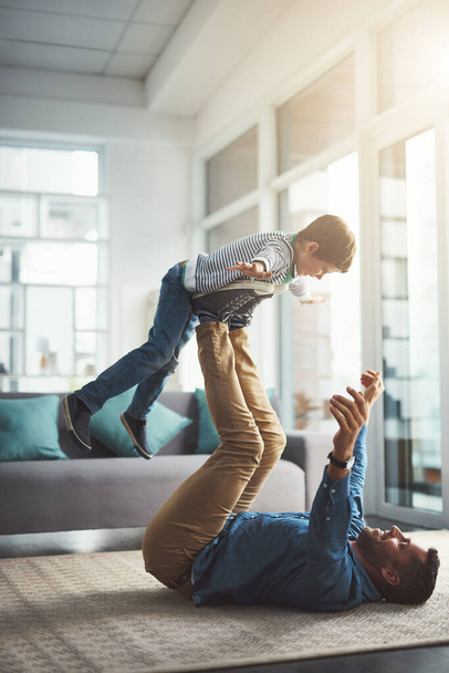 Im a superhero. a cheerful little boy playing around and being lifted by his dad with his legs in the living room at home during the day - Photo, Image