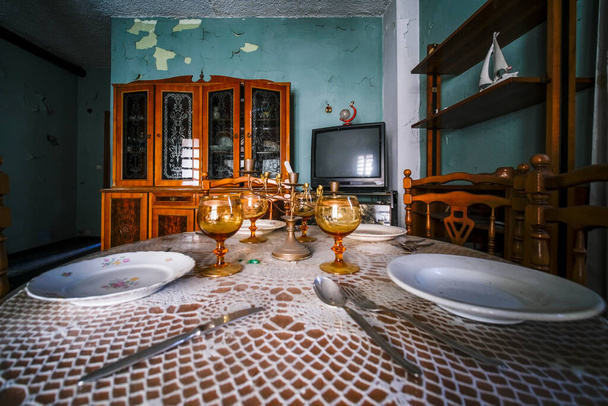 Tisch mit flachen Gläsern und Tischdecke in dem verlassenen Haus. Hochwertiges Foto - Foto, Bild