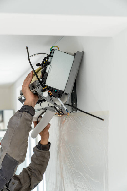 技術者は屋内で近代的なシステムエアコンを維持します。アパートでの専門的な気候制御サービスによるエアコンのインストール。換気システムの修理、メンテナンス - 写真・画像