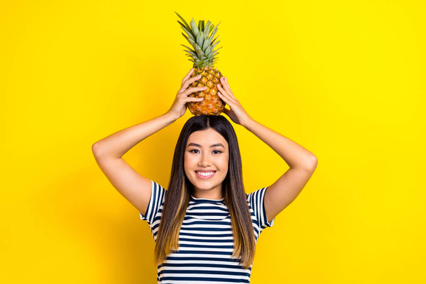 Photo of joking fooling japanese young woman hold hands head pineapple healthy tropical fruit smiling isolated on yellow color background. - Fotó, kép