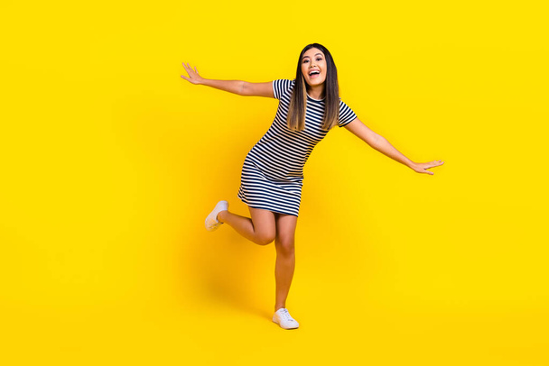 Full length photo of japanese girl wear striped dress have fun chill flying wings freedom party dance isolated on yellow color background. - Фото, зображення