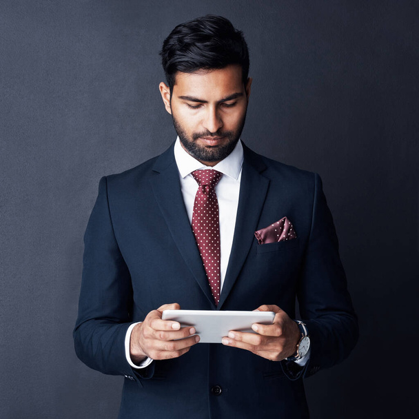 Working towards success in a smart world. Studio shot of a businessman using a digital tablet against a gray background - Fotografie, Obrázek