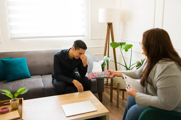 Mourning man crying and looking sad while talking about his passed away family member or partner and feeling depressed during a therapy session - Photo, Image