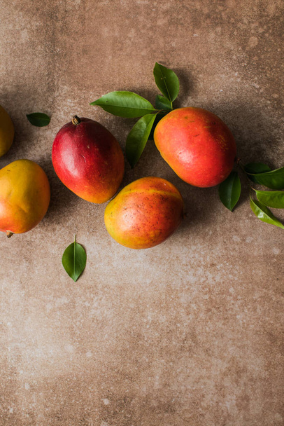 Mangó háttér tervezési koncepció. Friss mangó gyümölcs minta felülnézete levelekkel az asztalon. - Fotó, kép