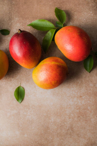 Mango Hintergrunddesign-Konzept. Draufsicht auf frisches Mangofruchtmuster mit Blättern auf dem Tisch. - Foto, Bild