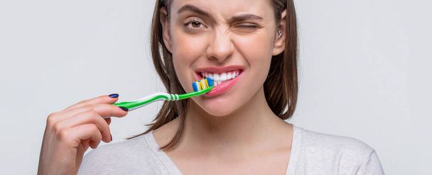 Closeup perfect and healthy teeth with toothbrush. Portrait smiling cute woman holding toothbrush. Smiling woman healthy beautiful teeth holding a toothbrush. - Foto, Imagem