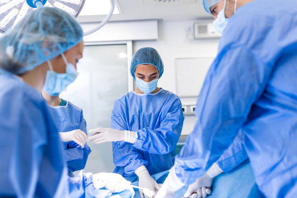 Tourné dans la salle d'opération, l'assistant distribue des instruments aux chirurgiens pendant l'opération. Chirurgiens Effectuer l'opération. Médecins professionnels effectuant une chirurgie. - Photo, image