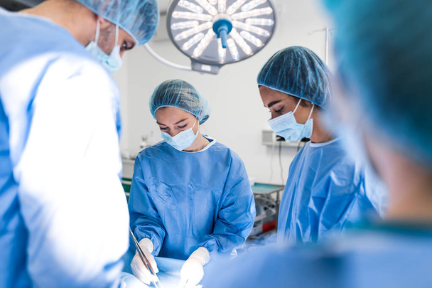 Urgent surgery. Professional smart intelligent surgeons standing near the patient and performing an operation while saving his life - Photo, image
