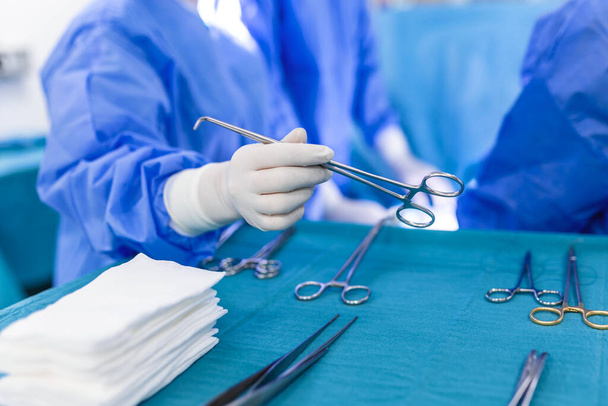 Neergeschoten in de operatiekamer, Assistent deelt instrumenten uit aan chirurgen tijdens de operatie. Chirurgen voeren operatie uit. Professionele artsen die chirurgie uitvoeren. - Foto, afbeelding
