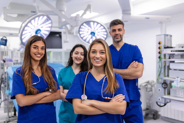 Closeup front view of group of mixed age doctors and nurses standing side by side and looking at the camera. Young female doctor is in the front. - Фото, изображение