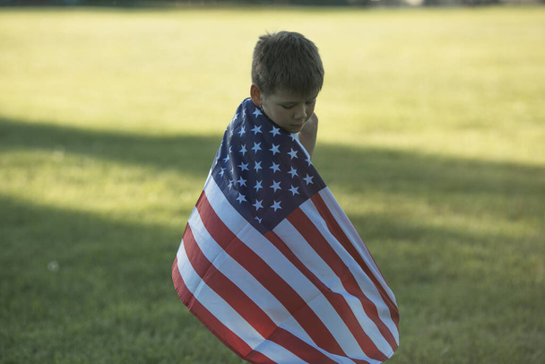 Niño celebrando de julio, 4 Día de la Independencia de los EEUU. Niño corriendo con bandera americana símbolo de Estados Unidos sobre campo de trigo. - Foto, imagen