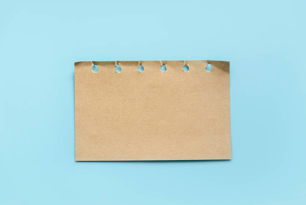 Vintage brown note paper isolated on a blue background. - Photo, Image
