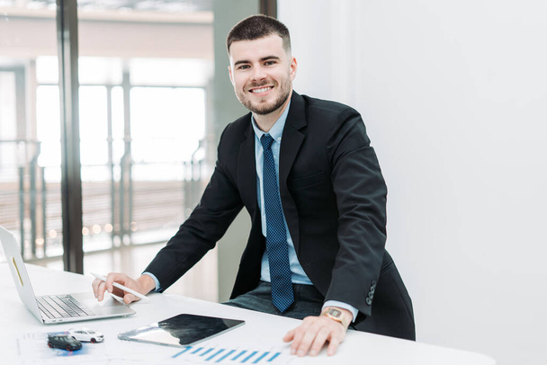 Νεαρός επιχειρηματίας χαμογελώντας εργάζεται στο γραφείο - Φωτογραφία, εικόνα
