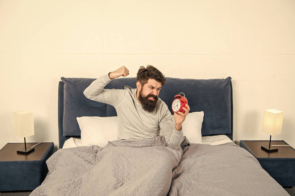 Angry man figting with alarm clock being in bed in morning, overslept. - Foto, afbeelding