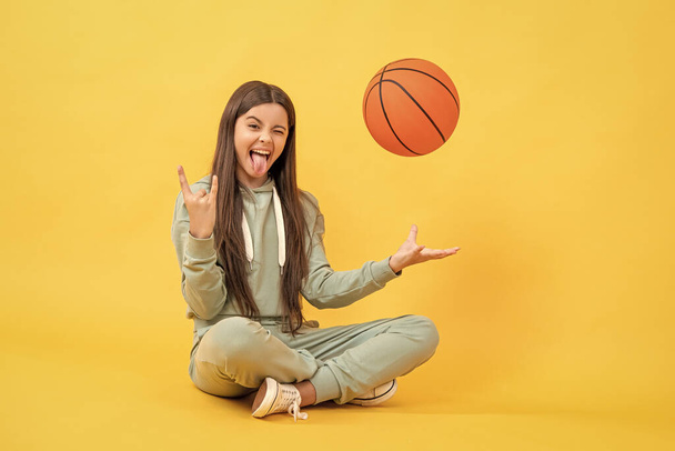 cool teen basketball girl in studio. teen basketball girl on background. photo of teen basketball girl with ball. teen basketball girl isolated on yellow. - Foto, afbeelding