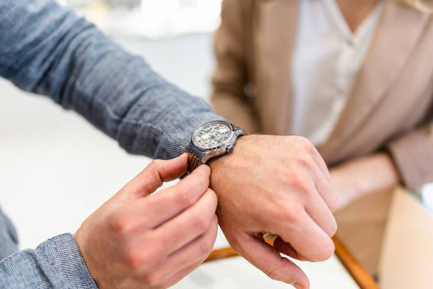 Elegant middle age businessman choosing and buying his new expensive watch. Beautiful young female seller helps him to make good decision. Fashion style and elegance concept. - Fotoğraf, Görsel