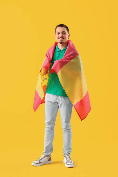 Przystojny młody człowiek z flagą Hiszpanii na żółtym tle - Zdjęcie, obraz