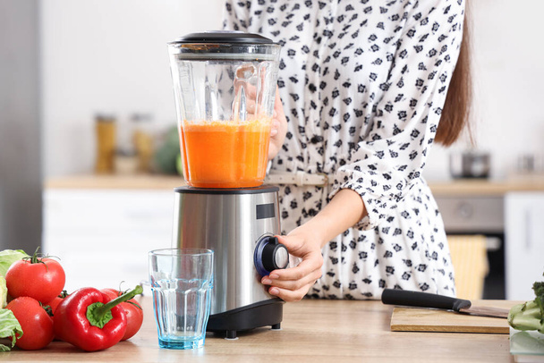 Young woman making vegetable juice with blender in kitchen, closeup - Foto, Imagen