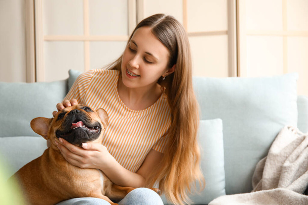 Young woman with cute French bulldog sitting on sofa at home - Foto, Imagem