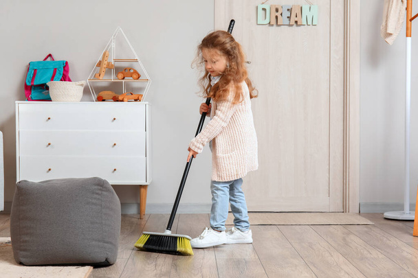 Cute little girl sweeping floor with broom at home - Foto, Imagen