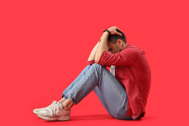 Young man having panic attack on red background - Photo, Image