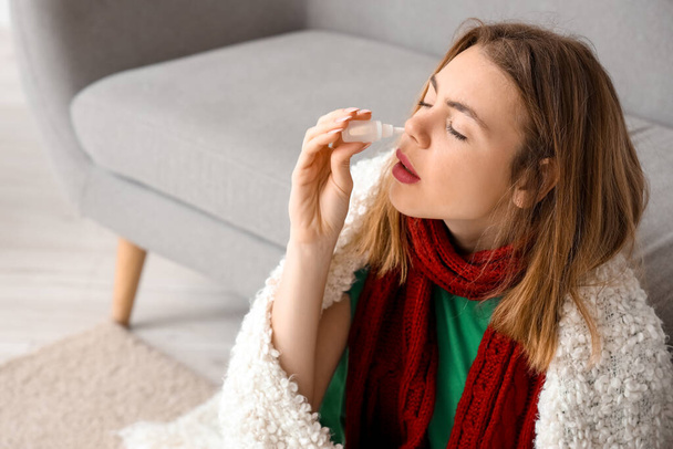 Malade jeune femme avec des gouttes nasales à la maison, gros plan - Photo, image