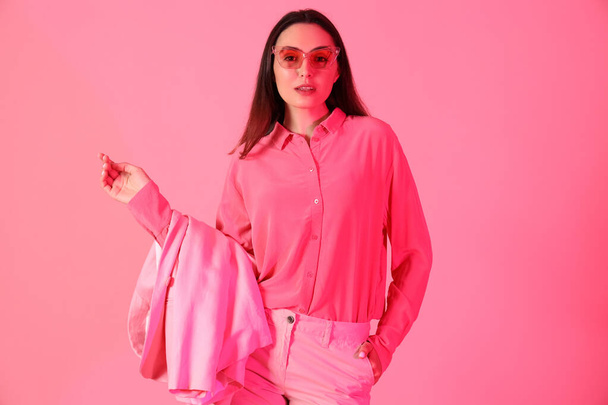 Jonge vrouw in stijlvol pak op roze achtergrond - Foto, afbeelding