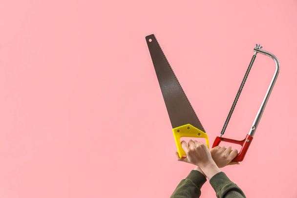 Female hands holding different saws on pink background - Photo, Image