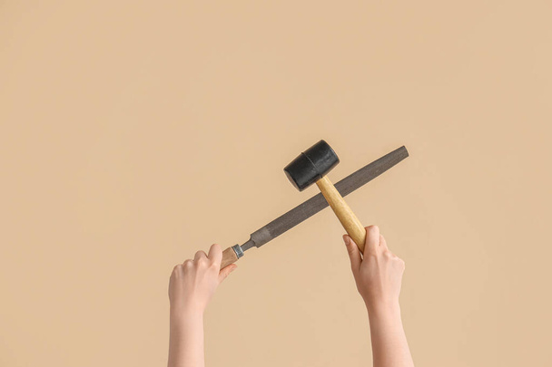 Female hands holding rubber mallet and rasp on beige background - Foto, imagen