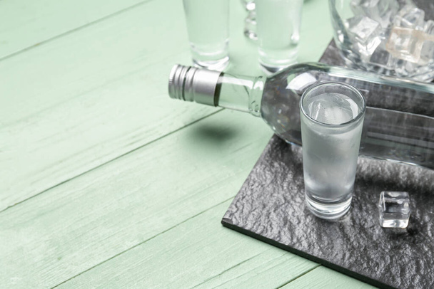 Butelka i szklanka zimnej wódki na zielonym drewnianym tle - Zdjęcie, obraz