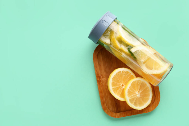Sports bottle of infused water and board with sliced lemon on turquoise background - Photo, Image