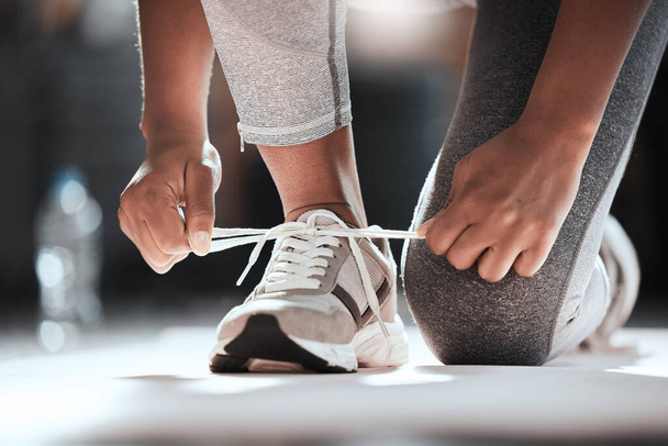 Hands, shoelaces and floor at gym with woman, fitness and ready for workout, wellness or training. Girl, sport shoes or sneakers for exercise, performance or health for lifestyle, motivation and club. - Foto, afbeelding
