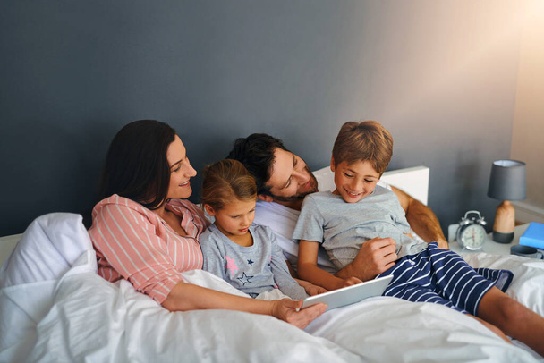 A qualquer hora é tempo de qualidade. uma jovem família usando um tablet enquanto se refrescam na cama juntos em casa - Foto, Imagem