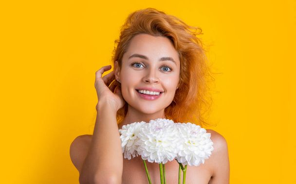portrait photo of woman with womens day chrysanthemum flowers. woman with womens day flowers isolated on yellow. woman with womens day flowers in studio. woman with womens day flowers on background. - Foto, afbeelding