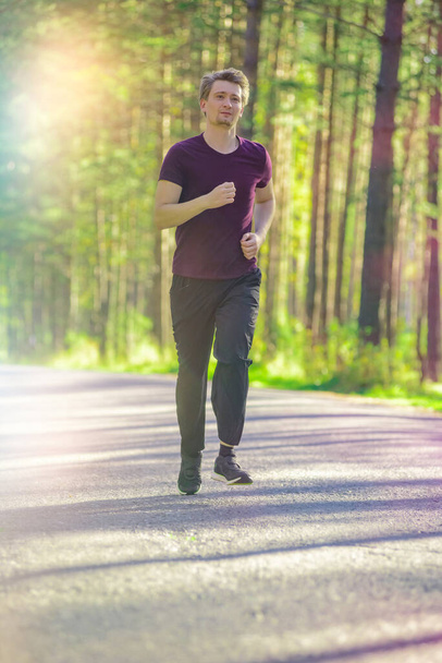 Running man jogging in city park at beautiful summer day. Sport fitness model caucasian ethnicity training outdoor. - Valokuva, kuva
