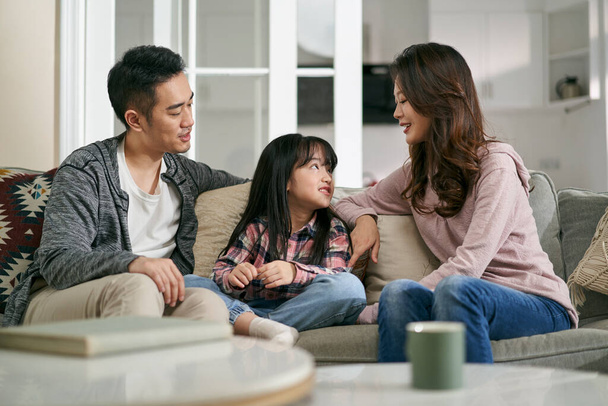 młody Azji matka i ojciec siedzi na rodzina kanapa w domu mając przyjemny rozmowa z córka - Zdjęcie, obraz