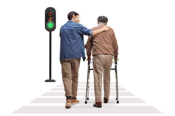 Rear view shot of a young man helping an elderly man with a walker at a pedestrian crossing isolated on white background - Foto, Imagen