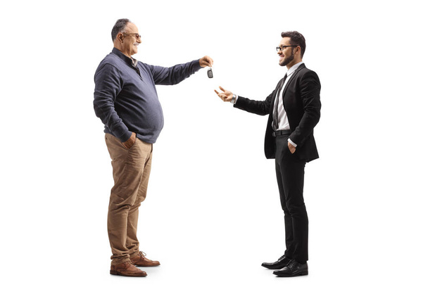 Mature man handing car keys to a businessman isolated on white background - Foto, imagen