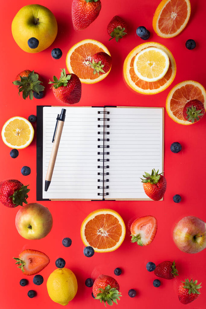 Refreshing food collection. background. apples oranges lemons, strawberries and blueberries. Summer vitamins levitate on a red background. Space for text. View from above. - Фото, изображение