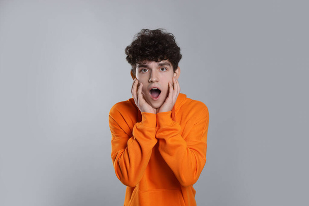 Portrait of shocked teenage boy on light grey background - Photo, Image