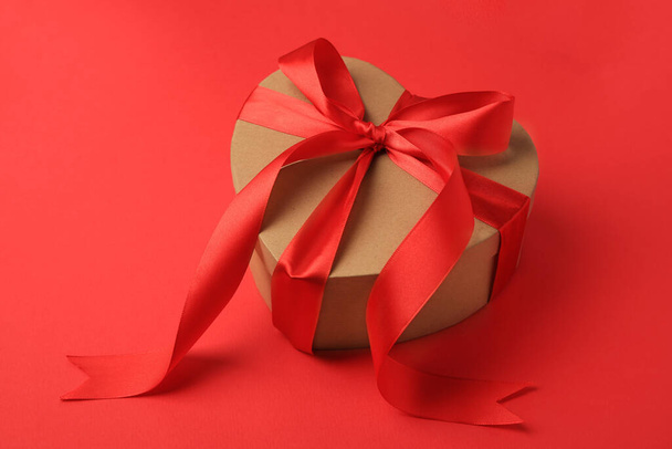Beautiful heart shaped gift box with bow on red background - Фото, зображення