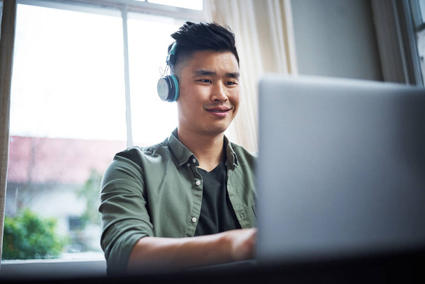 En su elemento creativo. un joven guapo escuchando música mientras trabaja desde casa - Foto, Imagen
