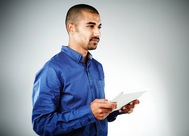 Gleiche Wettbewerbsbedingungen durch Technologie. Studioaufnahme eines jungen Geschäftsmannes mit seinem Tablet vor grauem Hintergrund - Foto, Bild